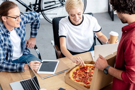 年轻人在一起工作时吃比萨饼的高角度视图
