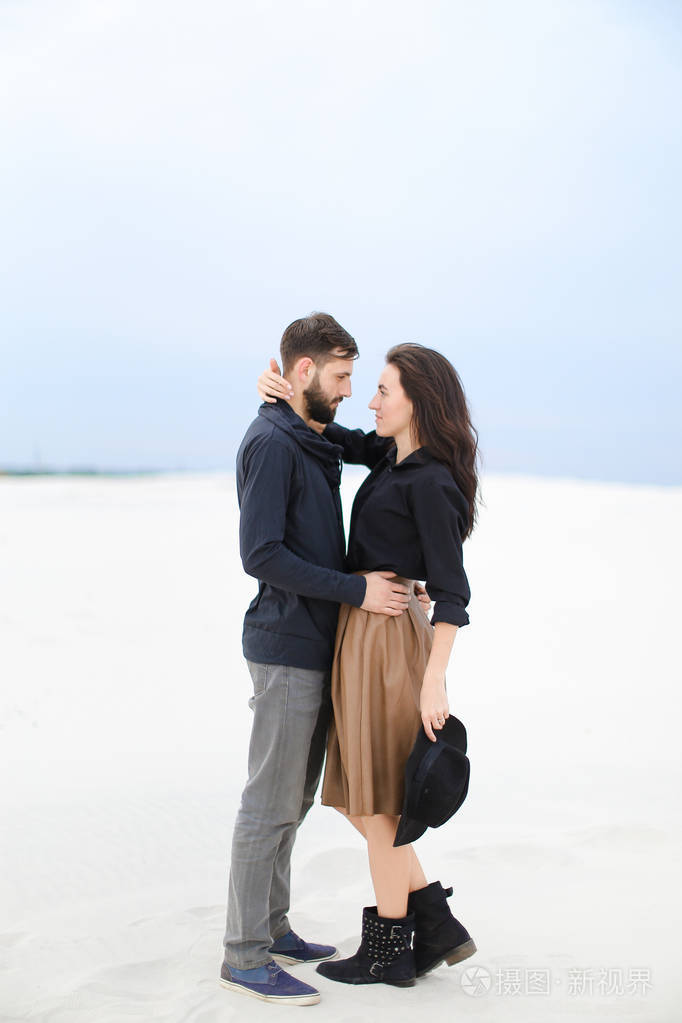 白种人好女人拥抱男人在冬天雪背景穿裙子黑色上衣和保持帽子