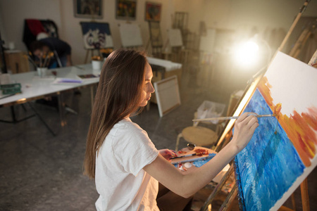 女画家在她的车间里画一幅油画画在画架上摄影棚的