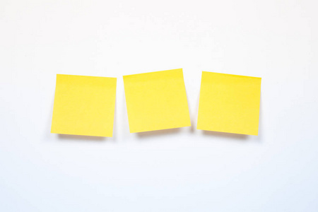 三黄色贴纸在白色背景, 空白黄色胶粘剂笔记在白色背景与阴影
