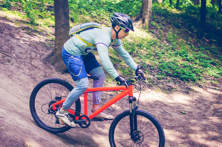 一个戴头盔的骑车的骑着橙色自行车从山上下山。