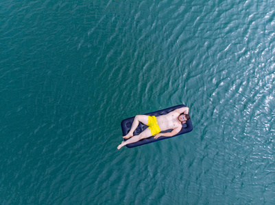 在蓝色的水床垫上的人。夏季时间概念。头顶视图