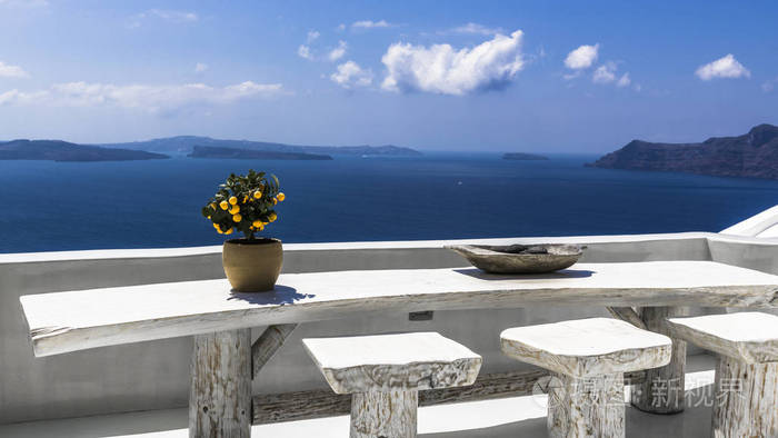风景如画的圣托里尼岛景观在一个大的木桌上橙树阳台可饱览古口的美景