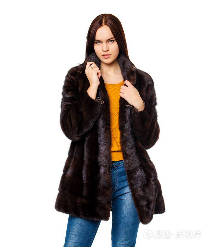 年轻漂亮的黑发妇女在毛皮貂皮大衣假扮白色孤立模特穿时髦的保暖衣服