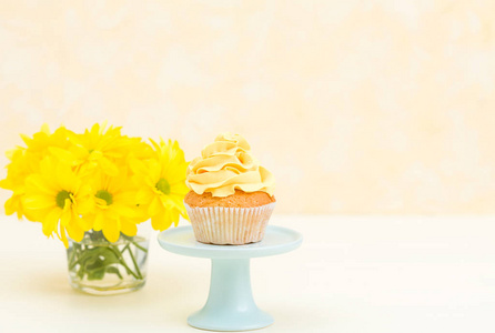 在柔和的背景下, 在玻璃花瓶上放上嫩黄色奶油装饰的蛋糕和菊花的花束。甜烤甜点贺卡