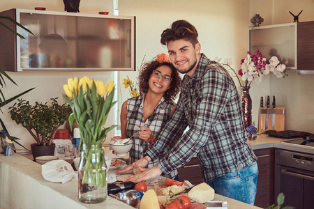 美丽的年轻夫妇在厨房做饭在家