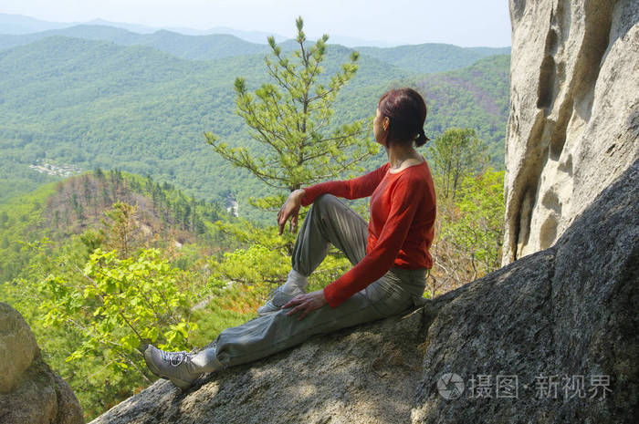 女人旅行者坐在悬崖边看着山谷