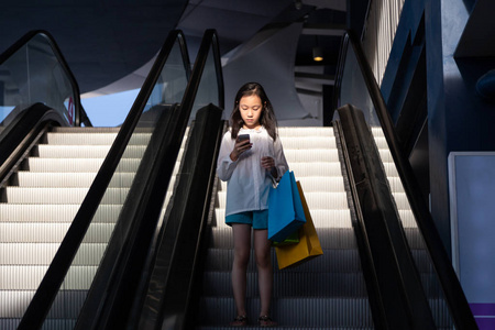 在商店购物后在自动扶梯上的亚洲女孩照片