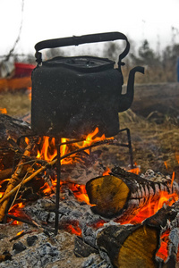 在木桩上的旅行者的烟雾缭绕的水壶。篝火