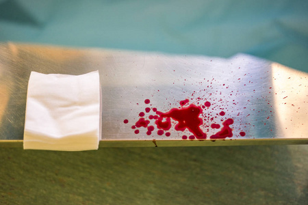 银色医院桌上的白色压缩和红色滴血照片