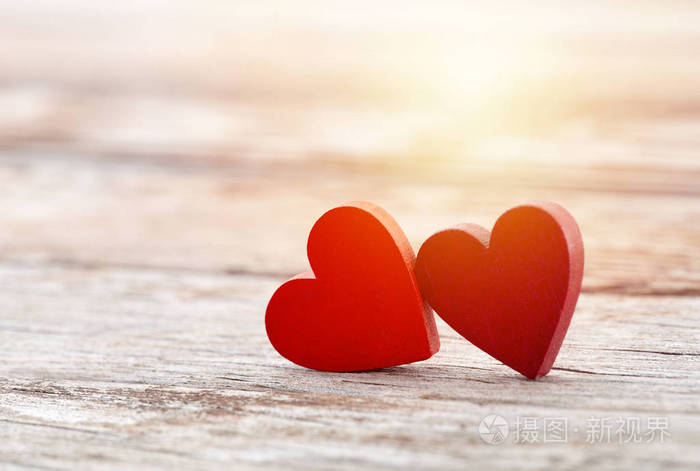 日落时两颗红心在木质背景上
