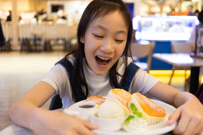 有魅力的快乐女孩坐着吃甜点 闭上一只饥饿的小女孩的肖像在餐厅吃