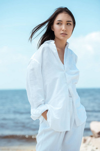 有吸引力的年轻亚洲妇女用手在口袋里看海滩