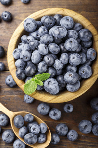 蓝莓的木质背景在盘子里, 在勺子里, 浆果散落在桌子上。从 abov 查看