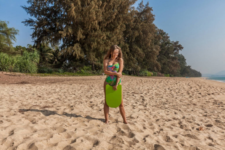 美丽的妇女与板站立在海附近与绿色板。普吉岛, 泰国