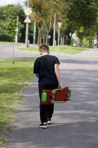 一个有滑板的少年。握着一只手里的滑板