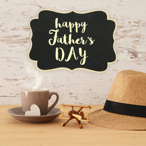 男子软呢帽帽子, 杯热咖啡或茶和飞机玩具在木桌上的形象。父亲节概念
