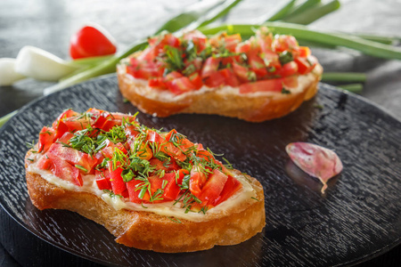 Bruschetta 用新鲜的西红柿和奶酪放在黑盘子里。特写