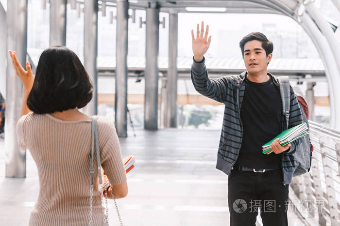 快乐的学生挥手和朋友打招呼