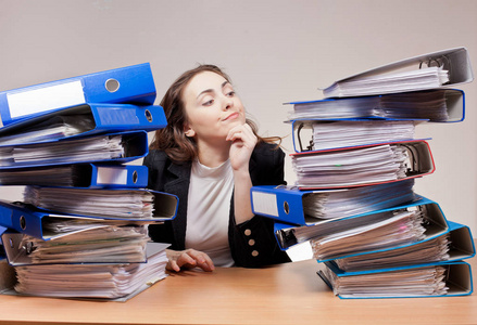繁忙的办公室工作.在办公室的文件夹和文件栈打乱了女实业家照片