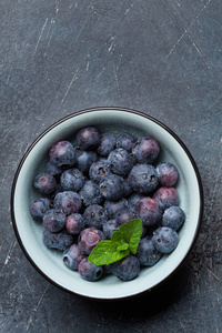 新鲜的夏天蓝莓在碗在灰色石头背景。具有文本空间的顶部视图