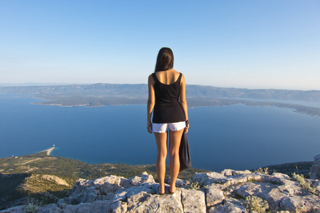 年轻女子在布拉克岛最高的山峰上看全景惊人的视图