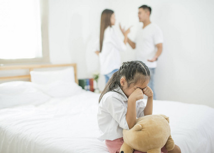 亚洲小女孩悲伤和哭泣, 而父母在卧室吵架, 家庭问题的照片设计和不愉快的概念