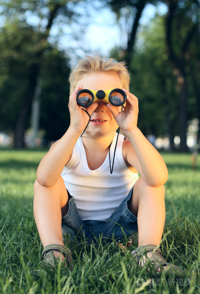 小男孩坐在公园的双筒望远镜