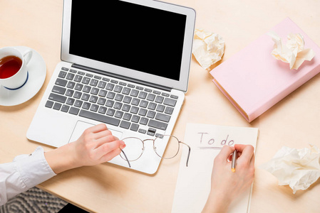 笔记本电脑上桌和女性手在工作顶部视图, 在笔记本中书写