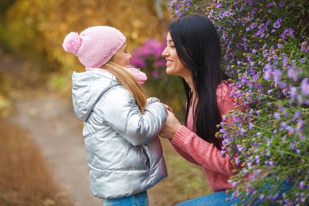 年轻美丽的母亲花时间与她的小可爱的女儿在秋季时间