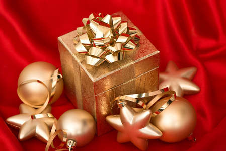 金色圣诞球上红色丝绸礼品盒