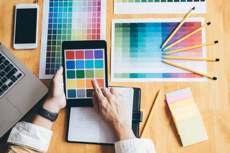 年轻的创意图形设计师使用图形板选择颜色样本图表选择着色的工作工具和配件在工作场所