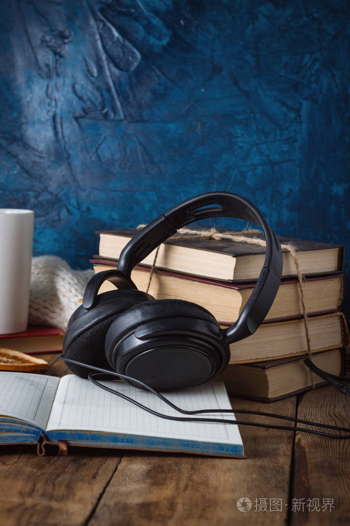 书是堆叠, 耳机, 白色的杯子, 打开的日记在一个木制背景.