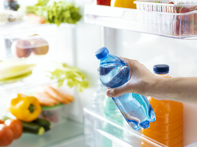 从冰箱饮料和水化概念中取出一瓶淡水的妇女