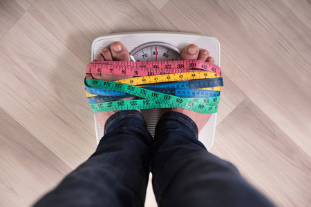 重色用多色卷尺包裹体重秤的人脚的特写照片