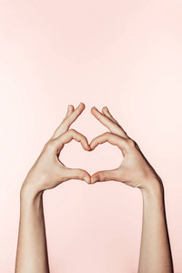 女性在粉红色背景下用手指做心脏符号的部分观点