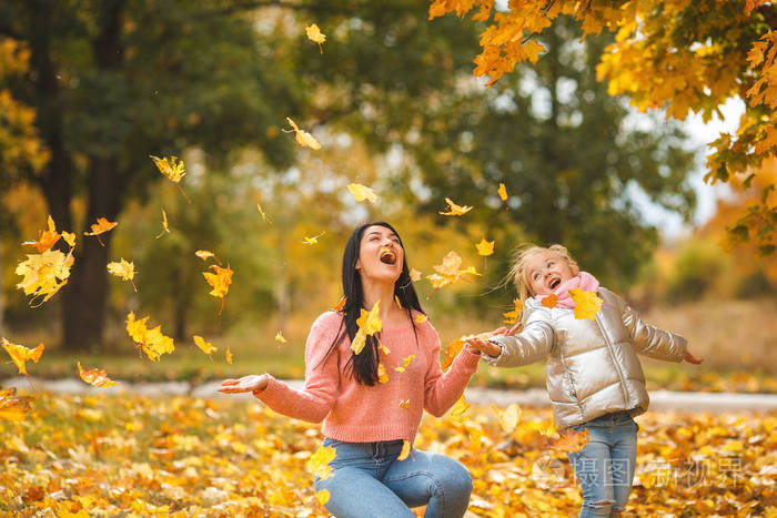 欢快的女孩玩黄叶快乐的母亲和小孩子在秋天的时间有乐趣