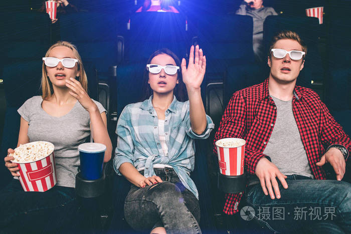 人们坐在电影院的椅子上感到惊讶和惊讶.