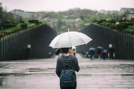 梨花雨年轻的亚洲女性旅行者在孤独的感觉抱着雨伞旅游在首尔, 韩国