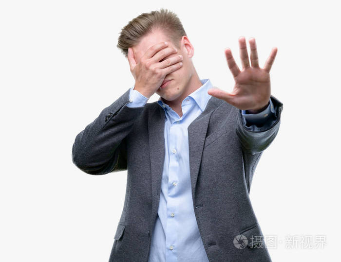 年轻英俊的金发商人用手捂着眼睛, 用悲伤和恐惧的表情做停止手势.