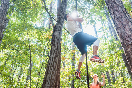 男子和女子攀登绳索在森林里运动