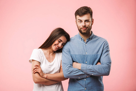 一个可爱的年轻夫妇的肖像站在与武器折叠孤立的粉红色背景
