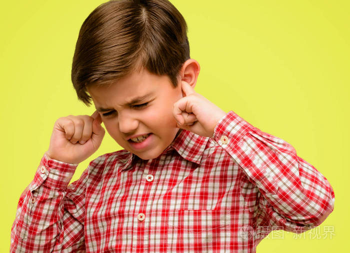 英俊的蹒跚学步的孩子用绿色的眼睛捂住耳朵, 忽略恼人的噪音, 堵住