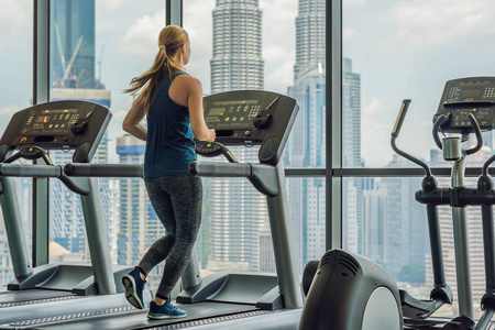 在一个大城市的背景下, 在健身房里锻炼跑步的美丽的年轻女子.