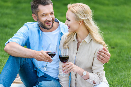 快乐的年轻夫妇拿着酒杯和微笑在野餐