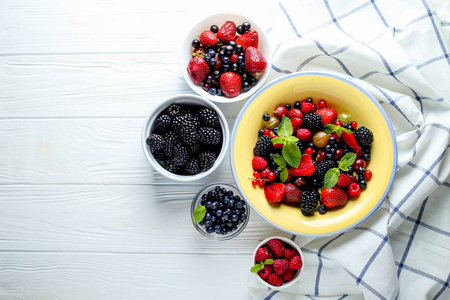 在木制背景下的碗浆果。组成的覆盆子, 醋栗, 草莓, 蓝莓, 醋栗, 黑莓和薄荷。健康, 饮食, 园艺。收获概念
