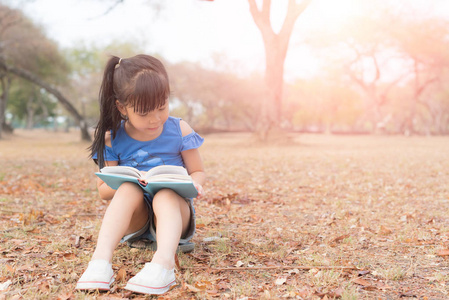 小女孩读一本书在树下