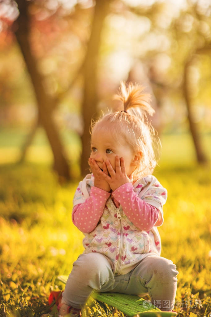 可爱开朗的小女孩, 金发女郎, 漫步在阳光灿烂的花园里