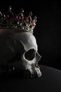 在黑色背景下, 一个戴着红色和金色宝石王冠的人头骨关闭