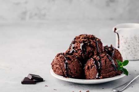 一盘巧克力冰淇淋勺, 上面有巧克力酱, 背景很轻。